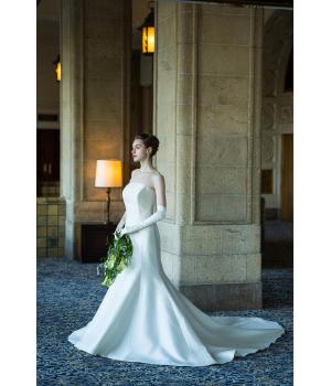 <span style='font-size:1.2em;'>3.スレンダーラインが似合うのはどんな花嫁様？</span><br>スレンダーラインは、実は体型だけで選ぶものではありません。<br><br>もちろん身体のラインを活かしたシルエットですが、ドレスの素材やデザイン、切り替え位置、ネックラインなどによって見え方は大きく変わります。<br><br>そのため、<br><br>・シンプルで洗練されたドレスが好き<br>・大人っぽく上品な雰囲気にしたい<br>・スタイルをすっきりと見せたい<br>・素材の美しさを楽しみたい<br>・甘すぎないドレスを探している<br><br>という花嫁様には、ぜひ一度ご試着いただきたいシルエットです。<br><br><br><br><span style='font-size:1.2em;'>4.選ぶときに注目したいポイント</span><br>〈シルエットだけで決めないこと〉<br><br>スレンダーラインを選ぶ際には、正面から見た印象だけでなく、<b>横から見たシルエット</b>や<b>後ろ姿</b>もぜひ確認してみてください。<br><br>ウェディングドレスは、挙式中やお写真など、後ろ姿を見られる時間も多いものです。<br><br>バックスタイルにレースやくるみボタン、トレーンなどシンプルなシルエットの中にも印象的な美しさが生まれます。<br><br><br>〈素材で雰囲気を選ぶ〉<br><br>同じスレンダーラインでも、素材によって印象は大きく変わります。<br><br>シルク：上品でクラシカル。光沢感が美しく、洗練された印象に。<br>レース：繊細で優美。やわらかく女性らしい雰囲気に。<br>チュール：軽やかで透明感のある印象に。<br>ビージング・刺繍：動くたびに繊細な輝きを感じる、華やかなスタイルに。<br><br>「どんな花嫁になりたいか」をイメージして素材を選ぶと、自分らしい一着に出会えると思います。<br><br><br><br><br><span style='font-size:1.2em;'>5.会場との相性</span><br>ドレス選びでは、ドレス単体の美しさだけでなく、会場の雰囲気とのバランスも大切です。<br><br>ホテルウェディングなら、シルク素材でクラシカルかつ品格のあるスタイルに。<br>自然光が入るナチュラルな会場なら、繊細なレースや軽やかな素材でやわらかな印象に。<br><br>「このドレスが好き」だけではなく、「この場所で、このドレスを着た姿はどんな花嫁に見えるか」まで想像してみると、よりイメージに近いドレス選びができるかと思います。<br>