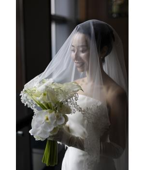 挙式では、ミカドシルク独特の光沢感と上質感はを活かした<br>シンプルでありながらゴージャスな雰囲気で。<br><br><br>柔らかなしっとりとしたチュールのヴェールが<br>花嫁さまを優しく包み込み、より一層美しく<br>引き立ててくれます。<br><br>ドレスのトレーンをヴェールが綺麗に囲む<br>バックスタイルに魅了されます。<br>