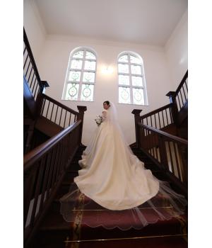 <span style='font-size:1.2em;'>05｜空間との調和</span><br>階段ショットは、ドレスと背景の美しい調和も魅力。<br><br>クラシカルな階段には優雅なロングトレーン、ラグジュアリーな空間には上質なシルク。<br><br>その場所の雰囲気とドレスが調和することで、一枚の写真により洗練された印象が生まれます。<br><br><br><br><br><br><span style='font-size:1.2em;'>06｜美しい「余白」を残す</span><br>あえて少し距離をとり、階段とドレスの広がりを一緒に写す。<br><br>そこに生まれる美しい余白が、階段ショットならではの優雅さを演出します。<br><br>華やかでありながら、どこか静かで上品。<br><br>時を経ても色褪せない、印象的な一枚に仕上がります。<br><br><br><br><br><br><span style='font-size:1.2em;'>07｜写真に残したいドレスを</span><br>ウェディングドレスを選ぶときは、着た瞬間の美しさだけでなく、「写真に残ったときの美しさ」にも目を向けてみてください。<br><br>階段に広がるスカートやトレーン、光を受ける素材の表情。<br><br>その一つひとつが、特別な日の記憶を美しく彩ってくれます。<br>