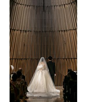 挙式は、あえてヘッドドレスは付けず、<br>柔らかなロングレースヴェールが<br>花嫁さんをそっと包み込み、<br>気品高く優美な佇まいを演出しています。<br>